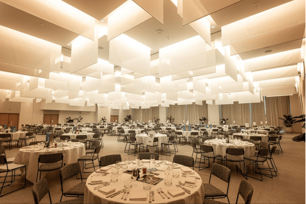 Ruime feestzaal van De Montil met ronde tafels en moderne verlichting, ideaal voor events met catering