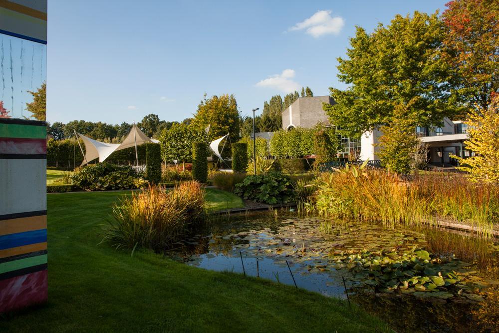 Rustige tuin met vijver en kunst bij een feestzaal