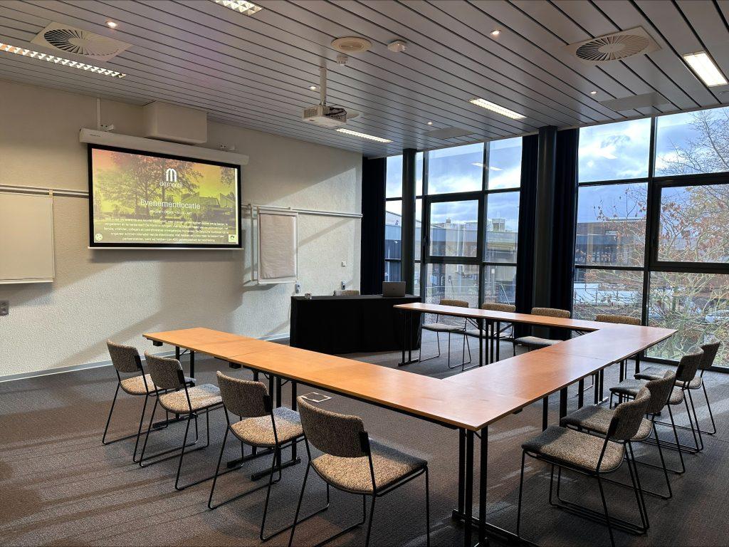 Vergaderzaal in De Montil met U-opstelling, beamer en scherm voor een interactieve meeting