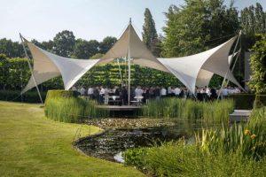 Personeelsfeest in de tuin van De Montil met gasten onder stijlvolle stretchtenten tijdens een outdoor receptie.