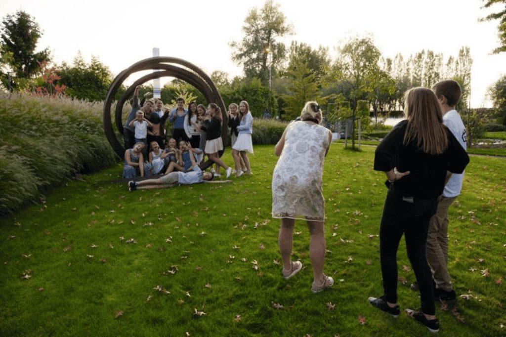 Groepsfoto van gasten tijdens een trouwfeest in een groene tuinsetting.