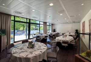 Lichte zaal van De Montil met gedekte ronde tafels en uitzicht op het terras, ideaal voor een intiem feest.