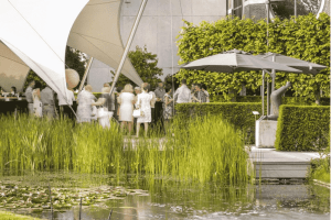Gasten vieren een lentefeest bij De Montil, onder een stijlvolle tent naast een vijver in een groene tuin
