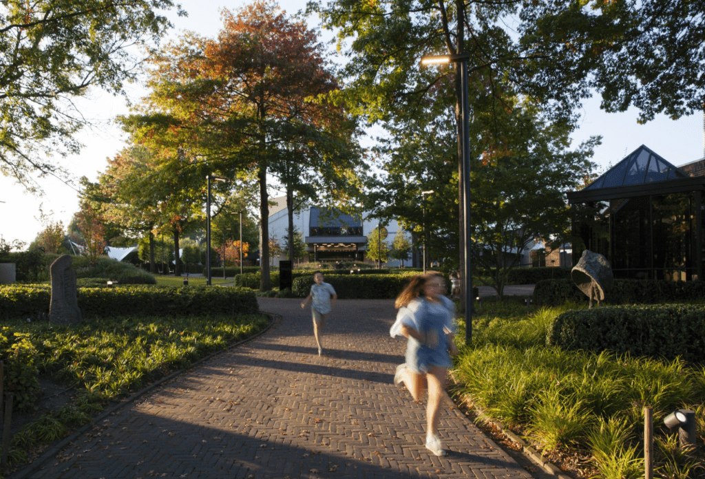 Kinderen wandelen en spelen op een zonnig tuinpad, omringd door groen, tijdens een lentefeest